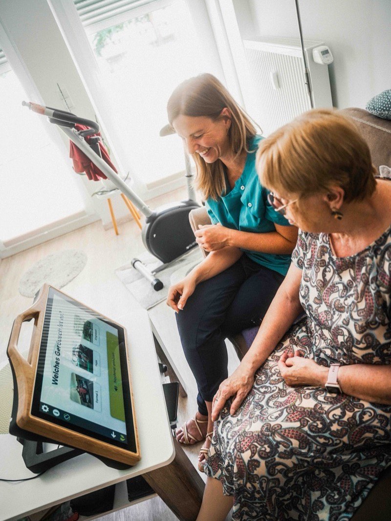 Betreuerin und Bewohnerin sitzen gemeinsam vor dem CareTable Mini
