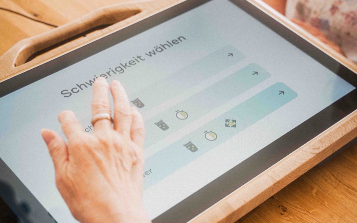 Hand wählt auf dem CareTable Mini den Schwierigkeitsgrad einer Übung